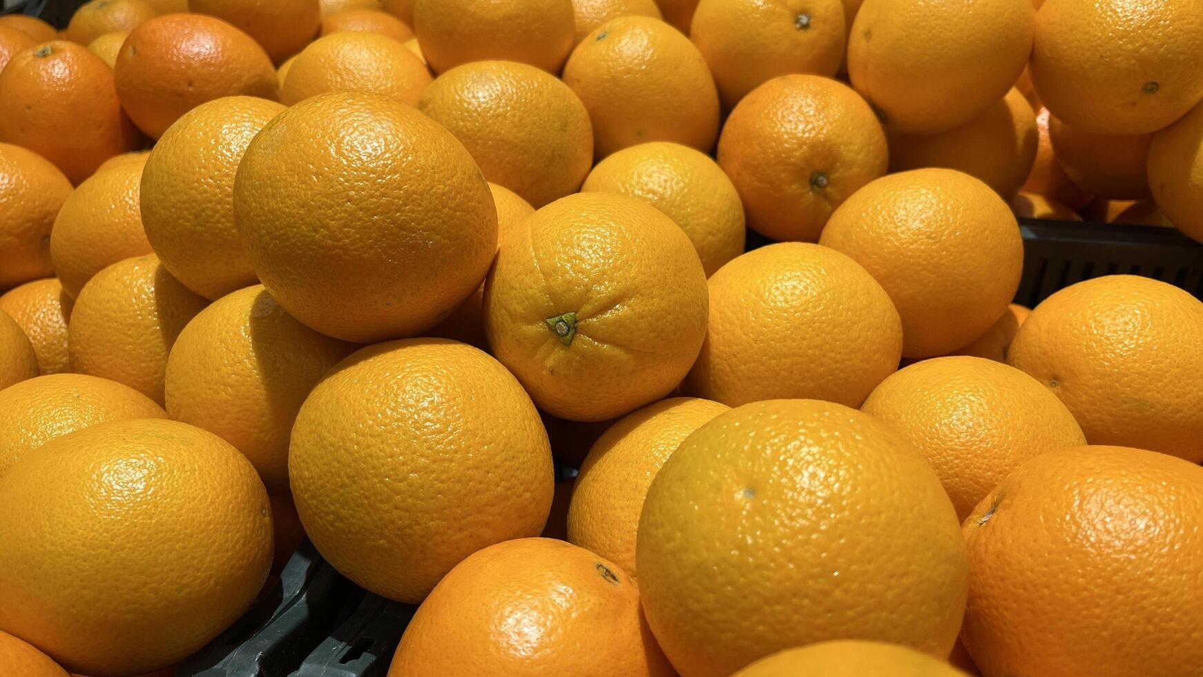 Close-up of a pile orange citrus fruit, ripe oranges stacked in a market display. Fresh and juicy. Citrus fruit background photo