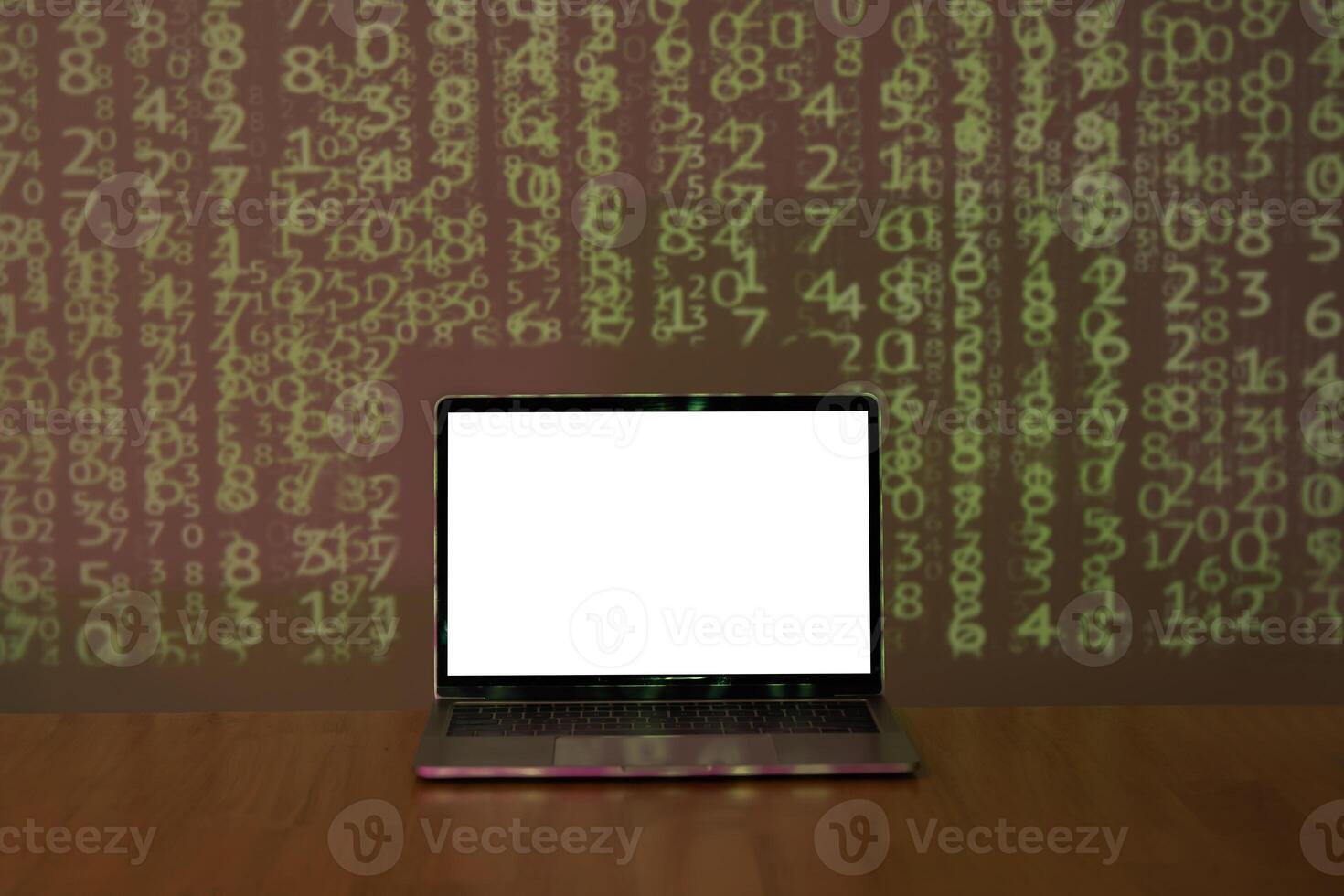 Laptop with space for your message on wooden table over binary code background in dark room. photo