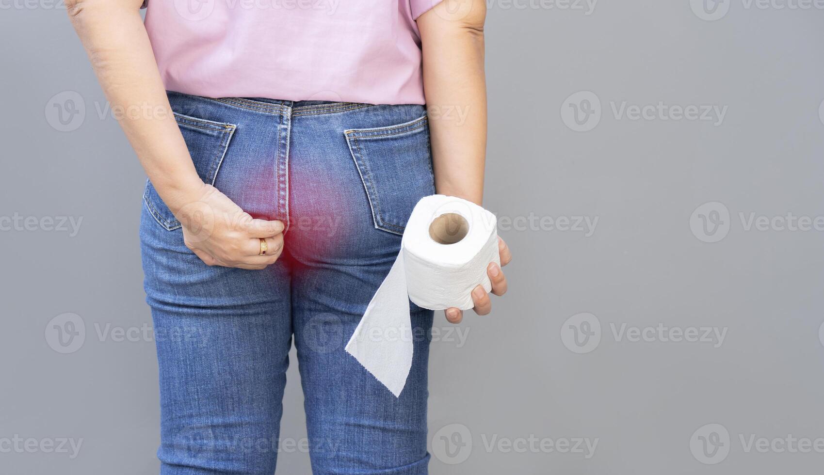 Woman with toilet paper suffering from hemorrhoid on light gray background photo