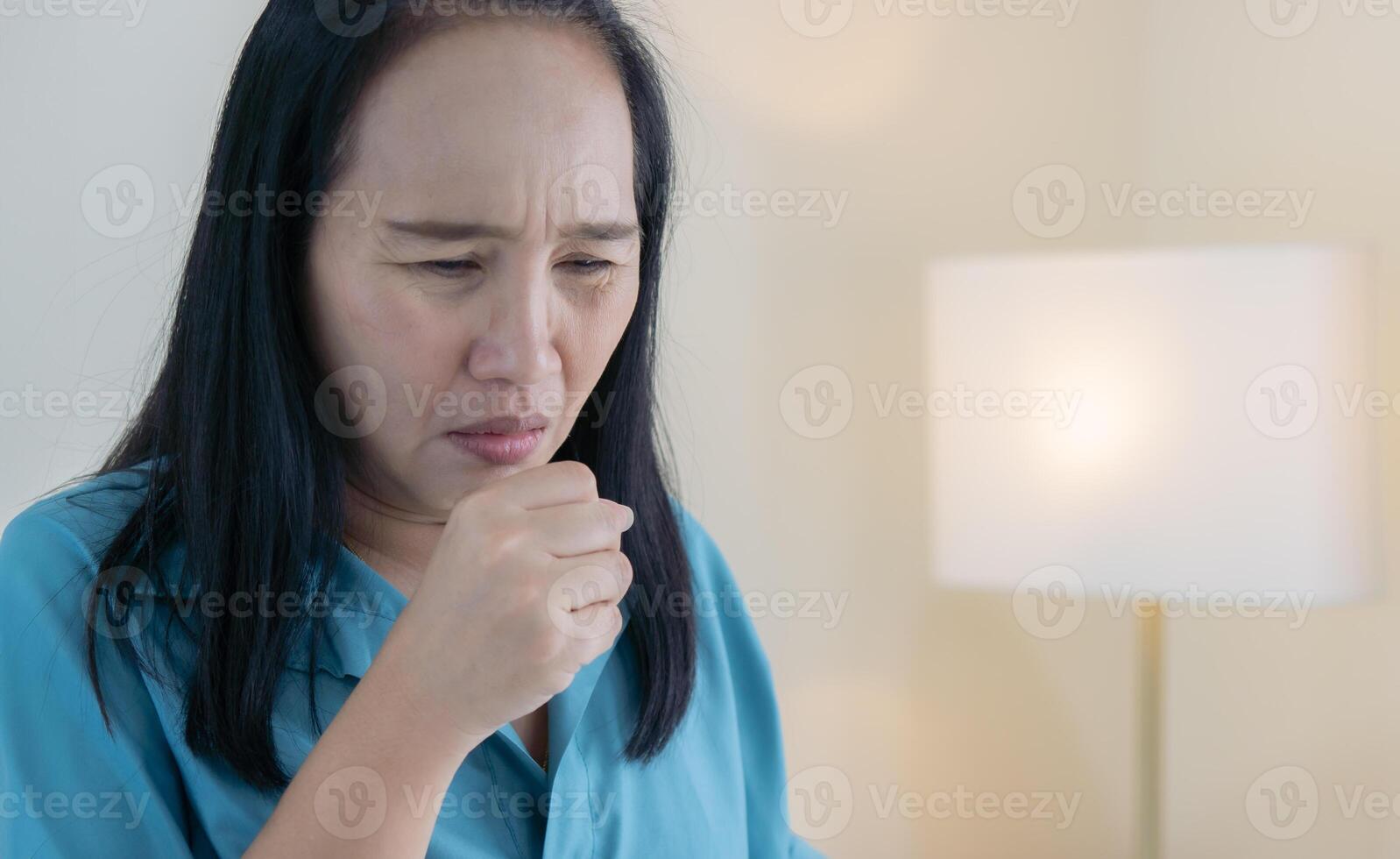 Cropped view of ill Asian female have a cough and sore throat at home with copy space. photo