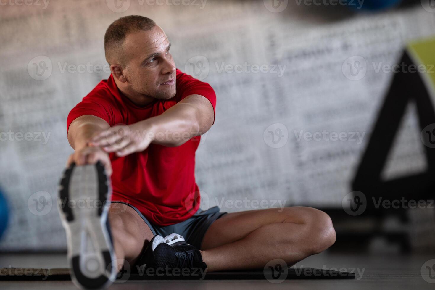 A fitness man stretches in the gym after an intense workout, focusing on recovery and flexibility. photo