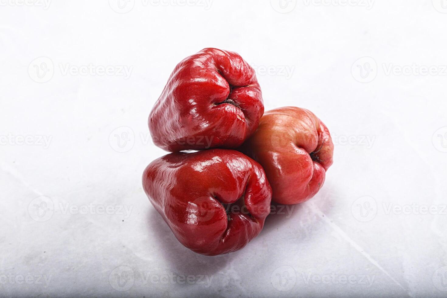 Three red peppers on a white surface photo