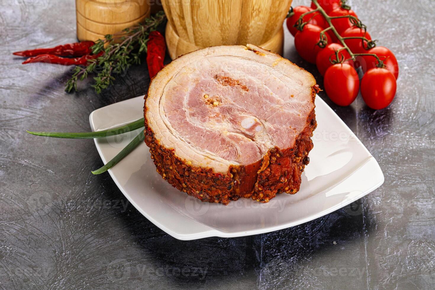 A ham on a plate with tomatoes and herbs photo