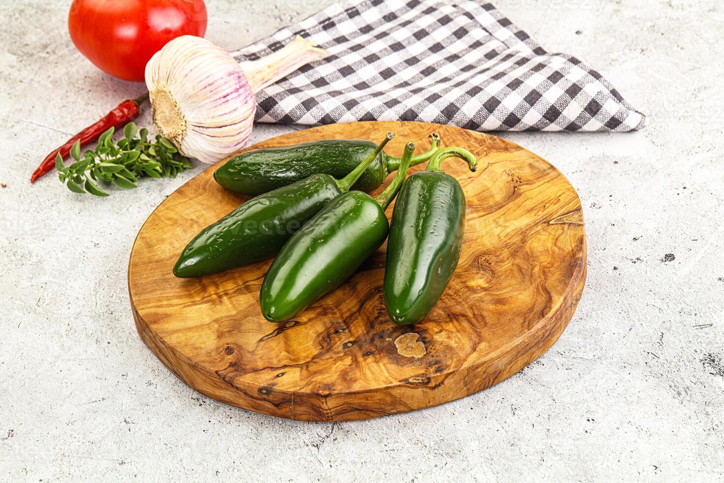 A wooden cutting board with three green peppers photo