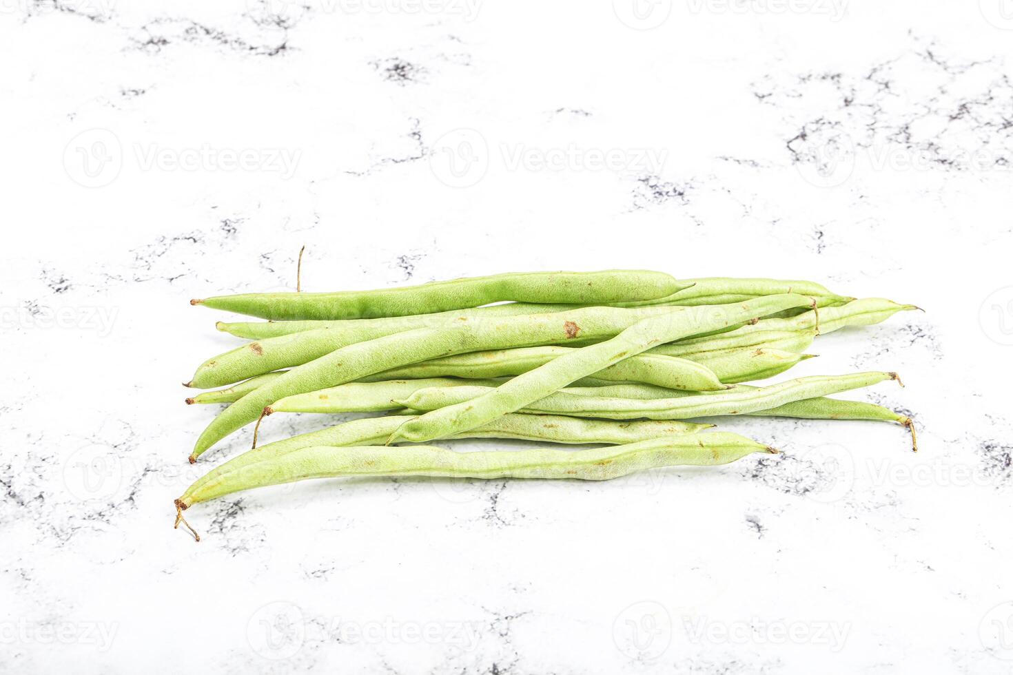 A bunch of green beans on a white surface photo