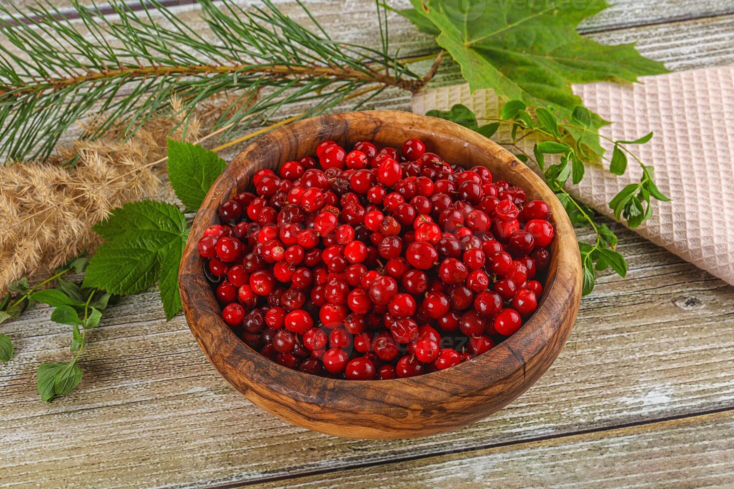 Red currant berries in a wooden bowl on a wooden table photo