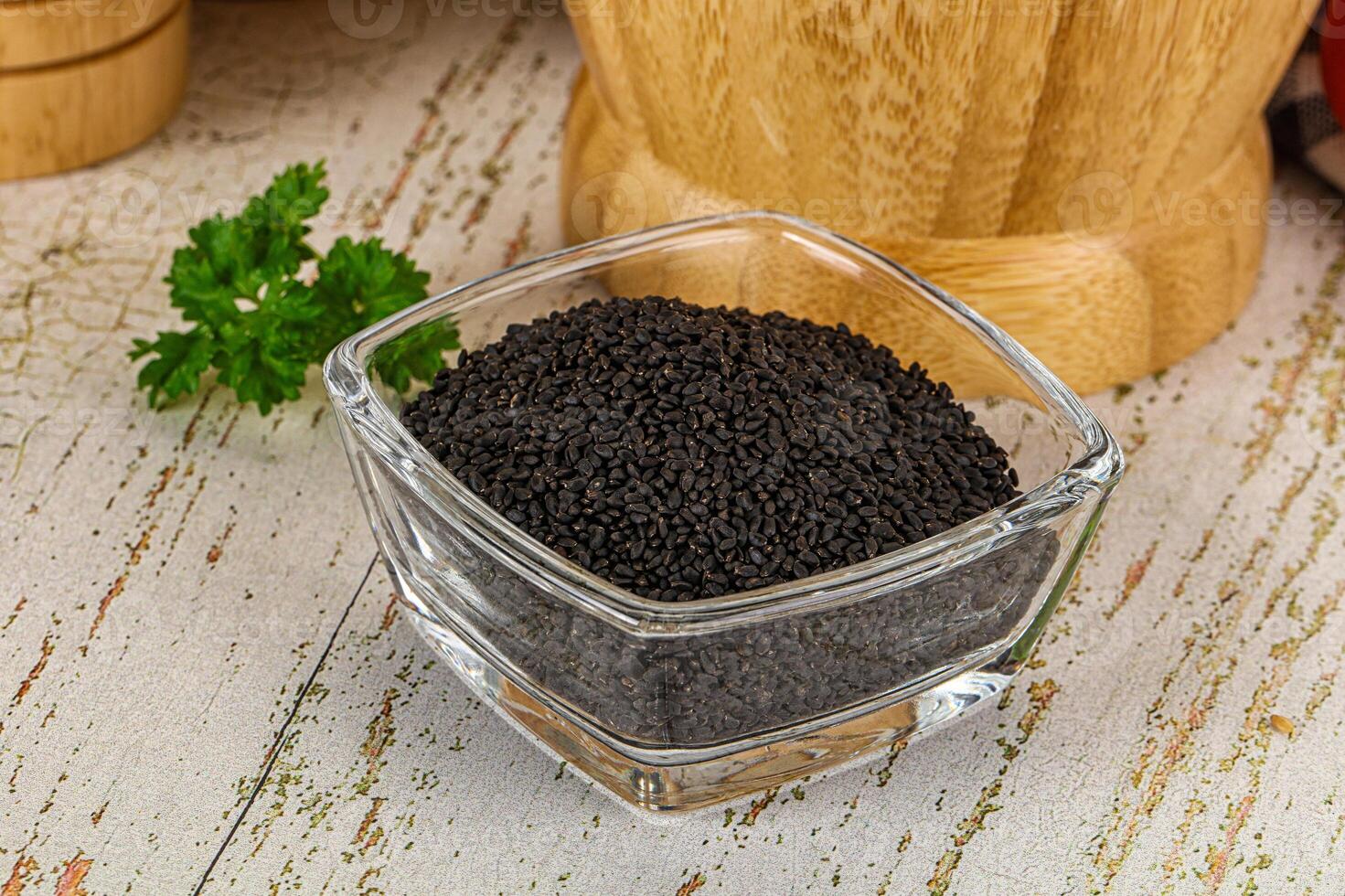 A bowl of black seeds on a table next to a knife photo