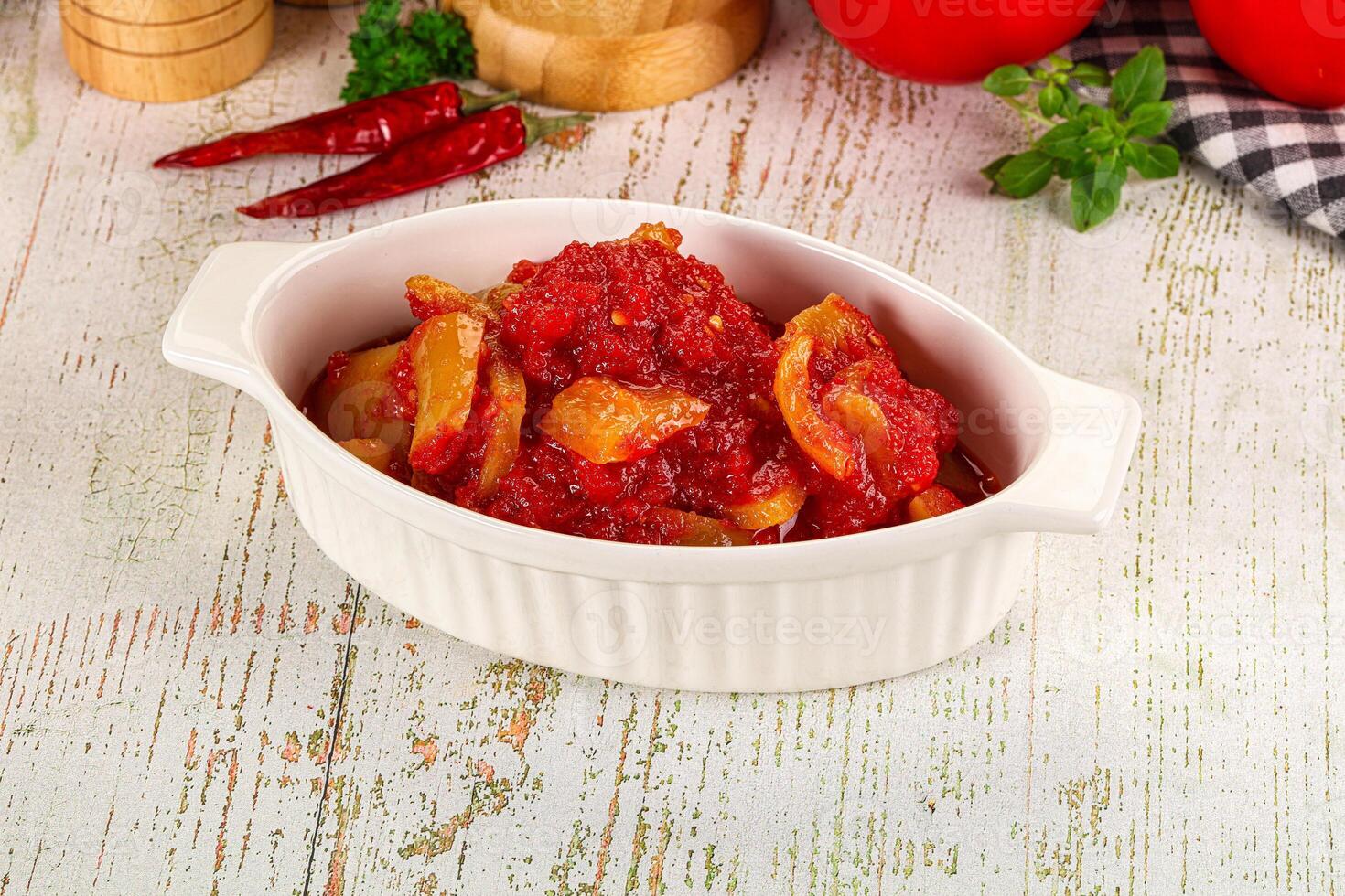 A bowl of tomato sauce on a table next to a knife photo