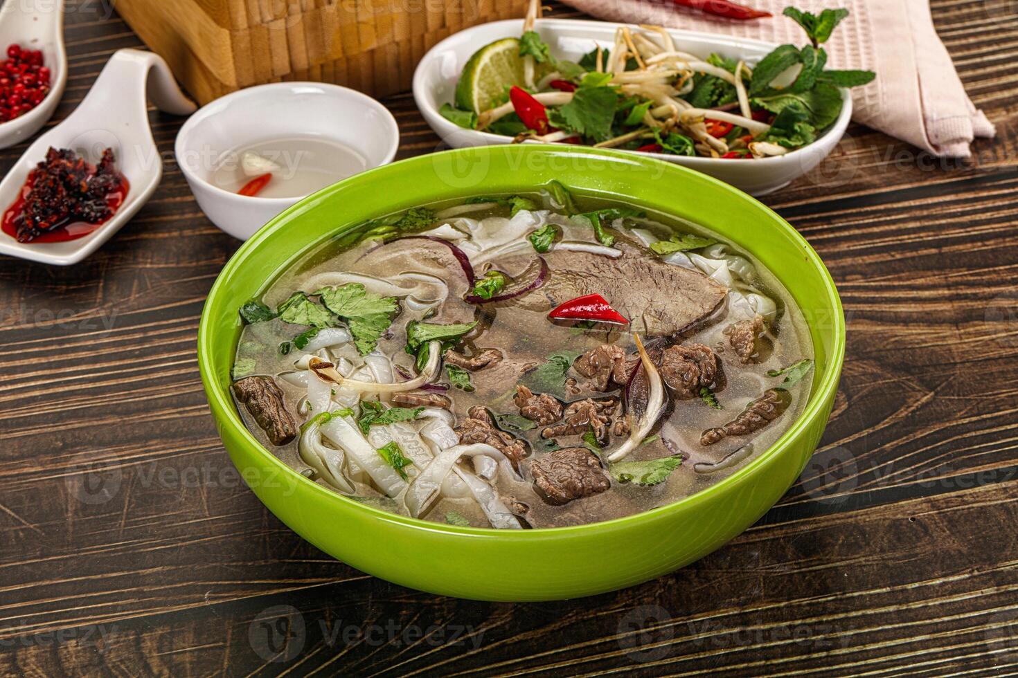 A bowl of soup with meat and vegetables on a table photo