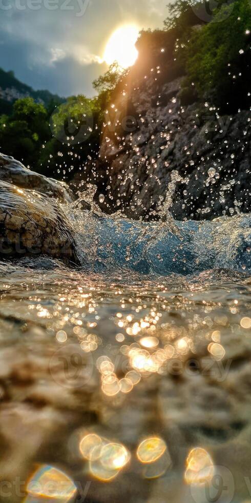 Water splashes over rocks near a sunlit riverbank photo