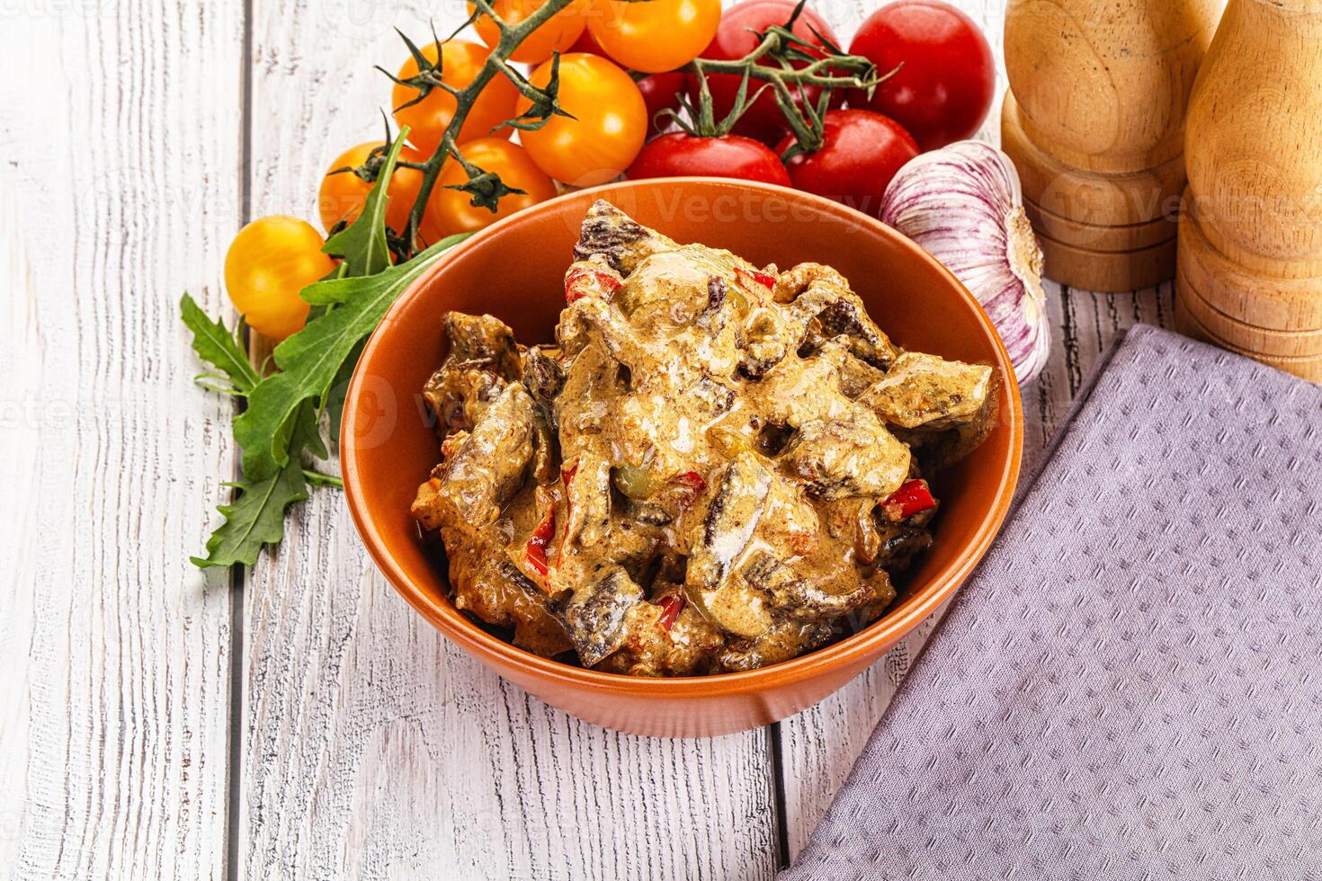 A bowl of food with vegetables and spices on a wooden table photo