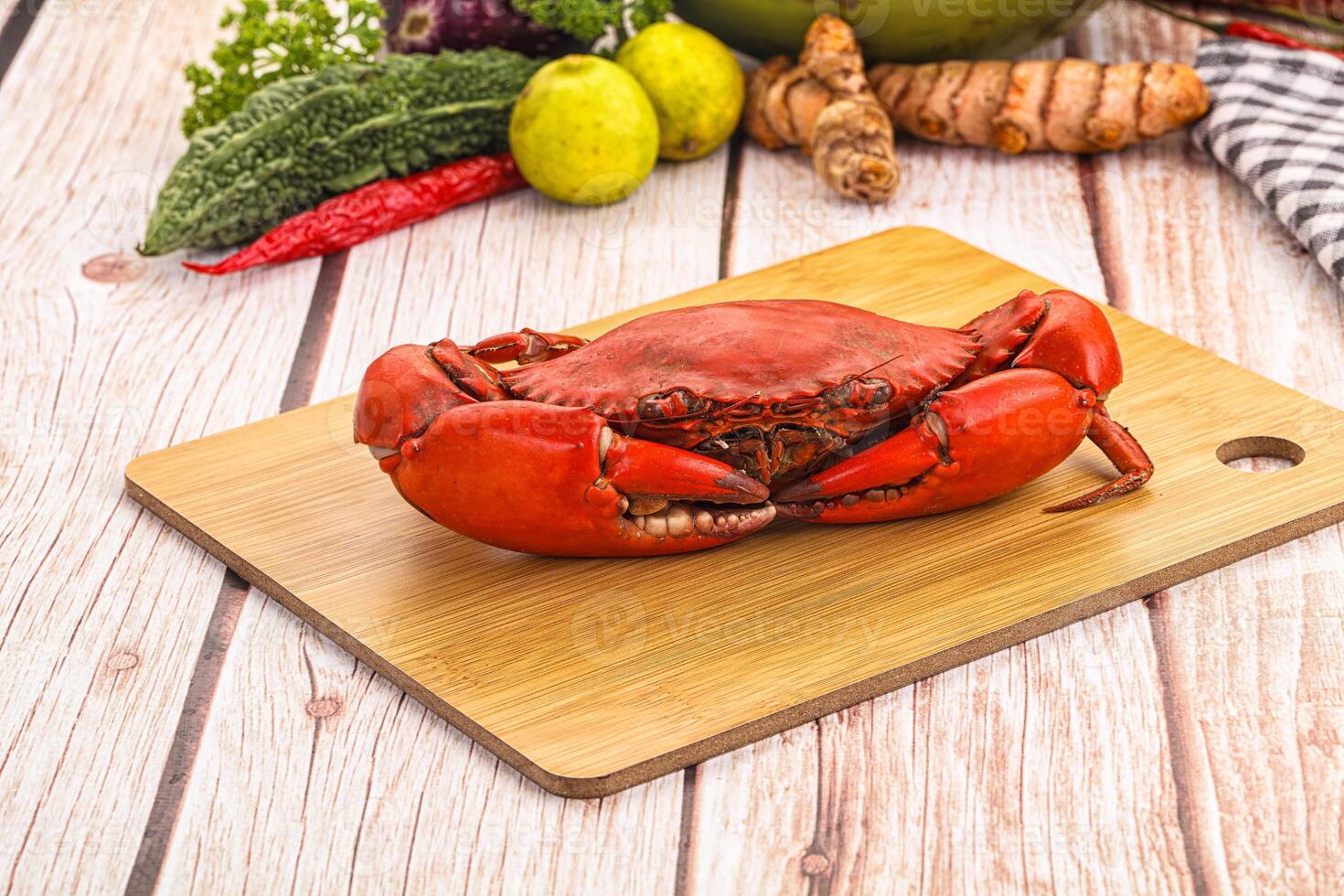 A crab on a cutting board with other vegetables photo