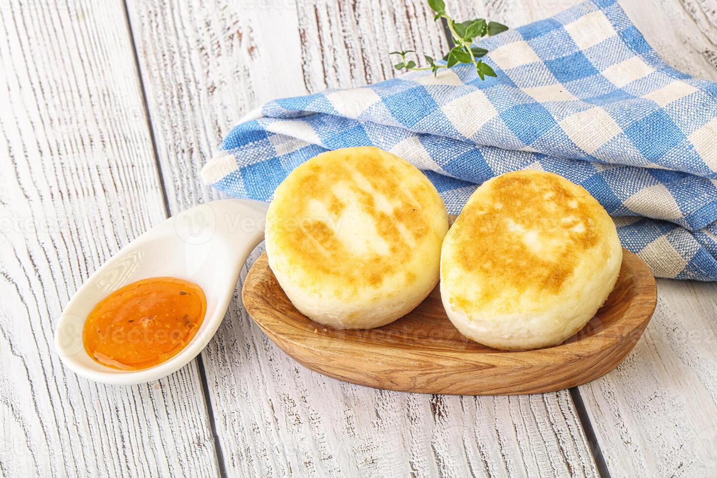 Two bread rolls on a wooden plate with a spoon of sauce photo
