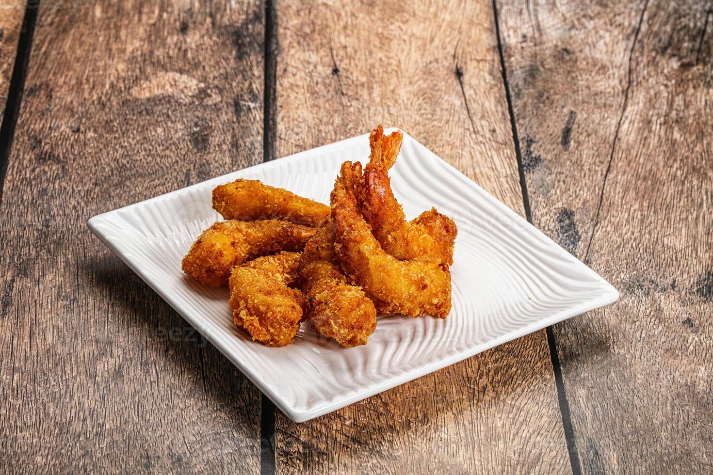 Fried shrimp on a white plate on a wooden table photo