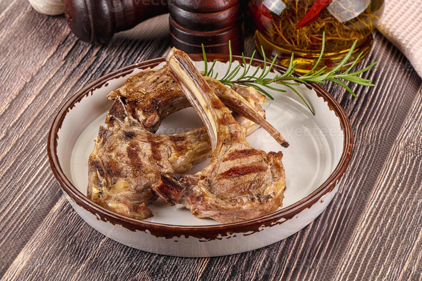 A bowl of meat with herbs and spices on a wooden table photo
