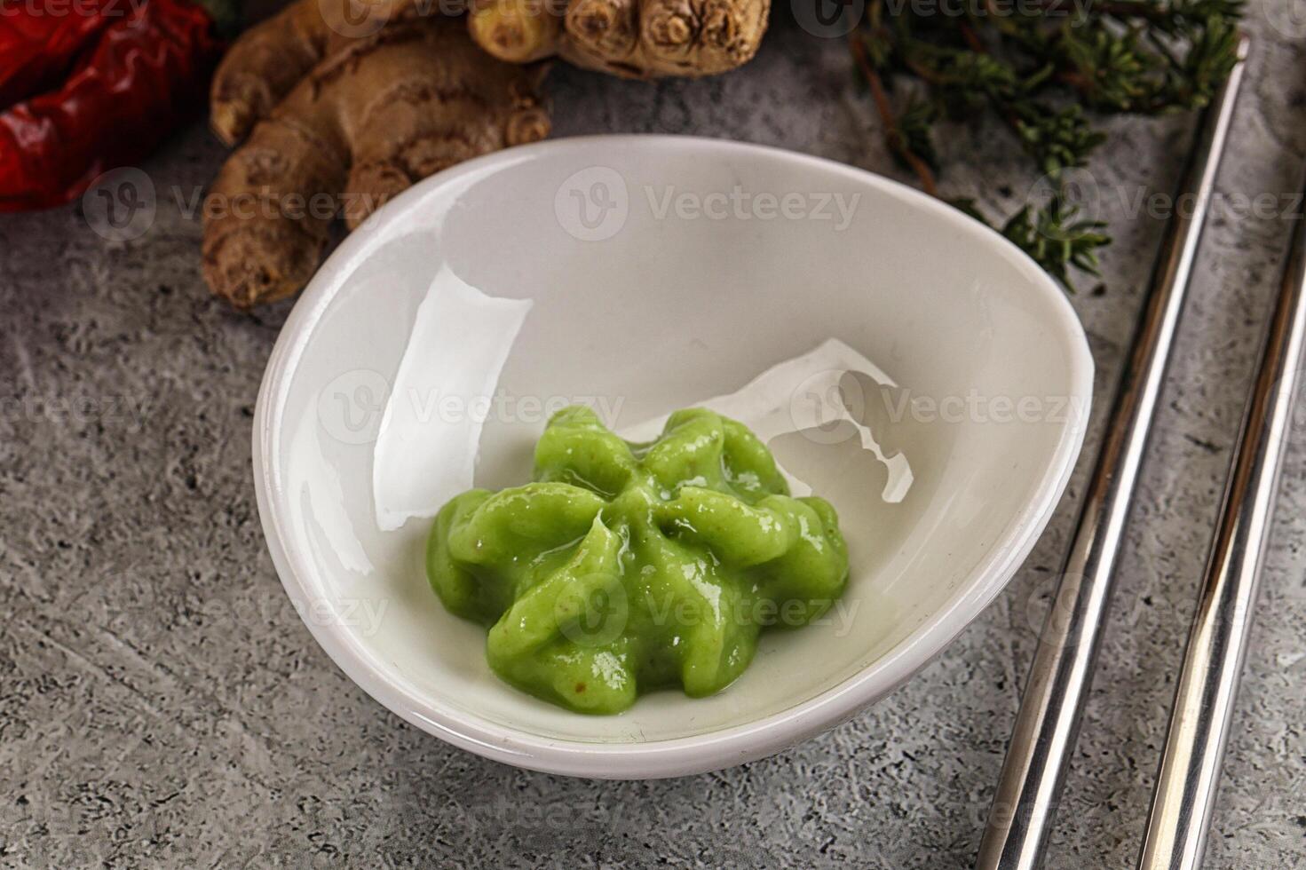 A bowl of green food with chopsticks and ginger photo