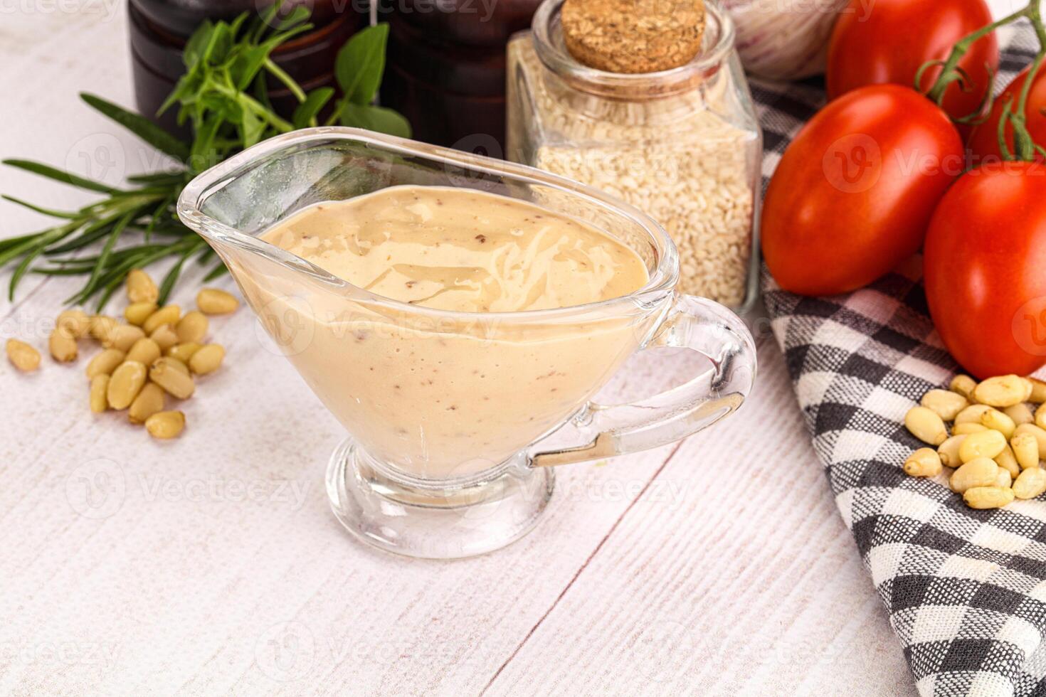 A glass of dressing on a table next to tomatoes, garlic and other ingredients photo
