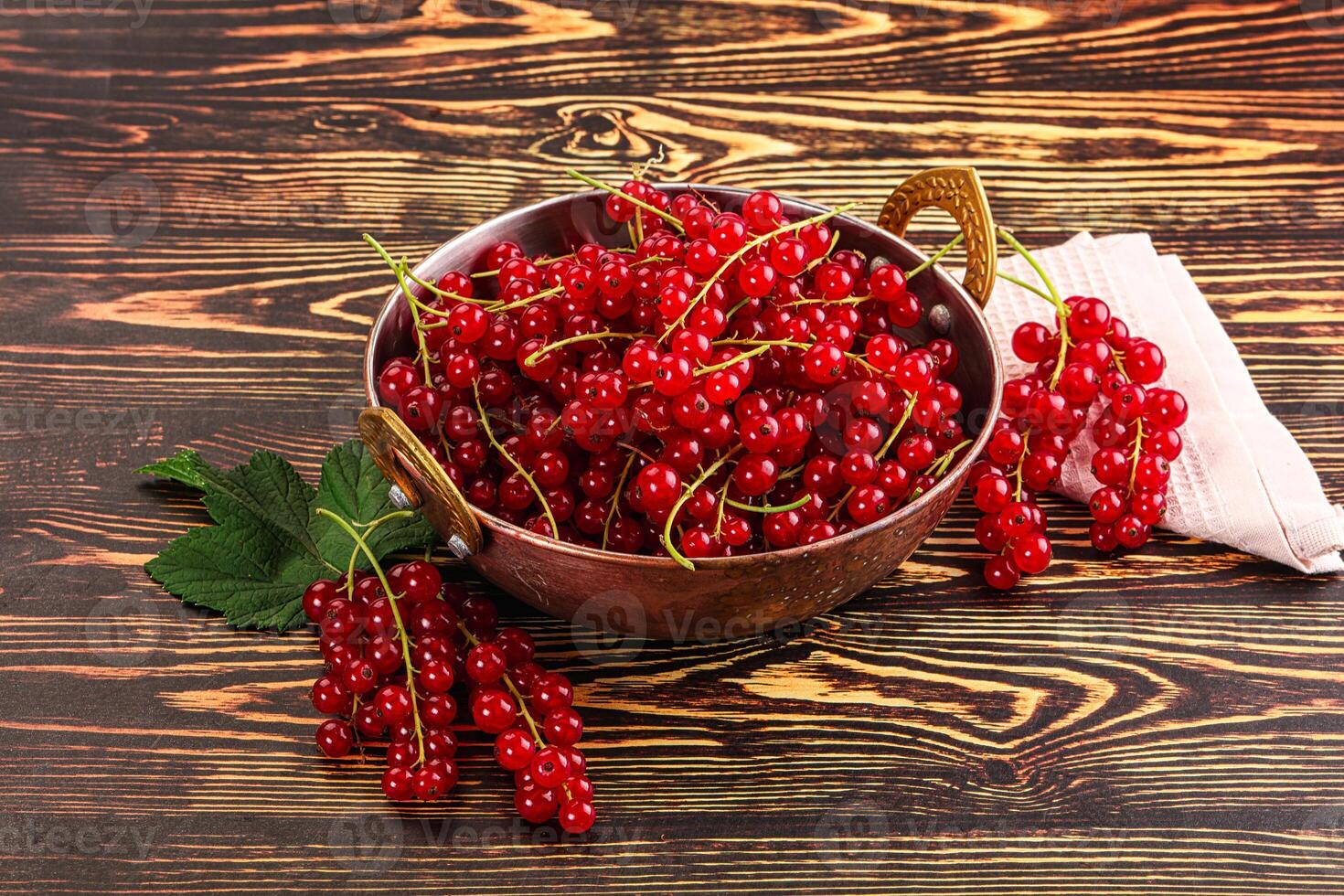A bowl of red currants on a wooden table photo