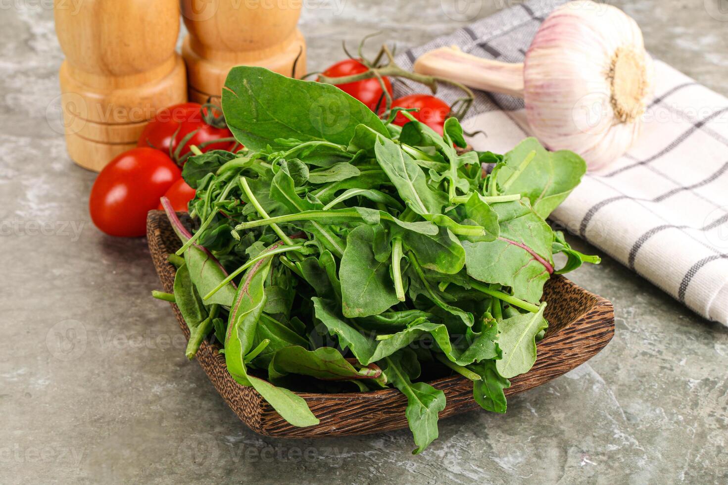 A wooden bowl filled with spinach and tomatoes photo