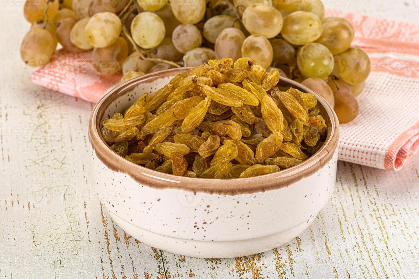 A bowl of raisins and a bunch of grapes photo