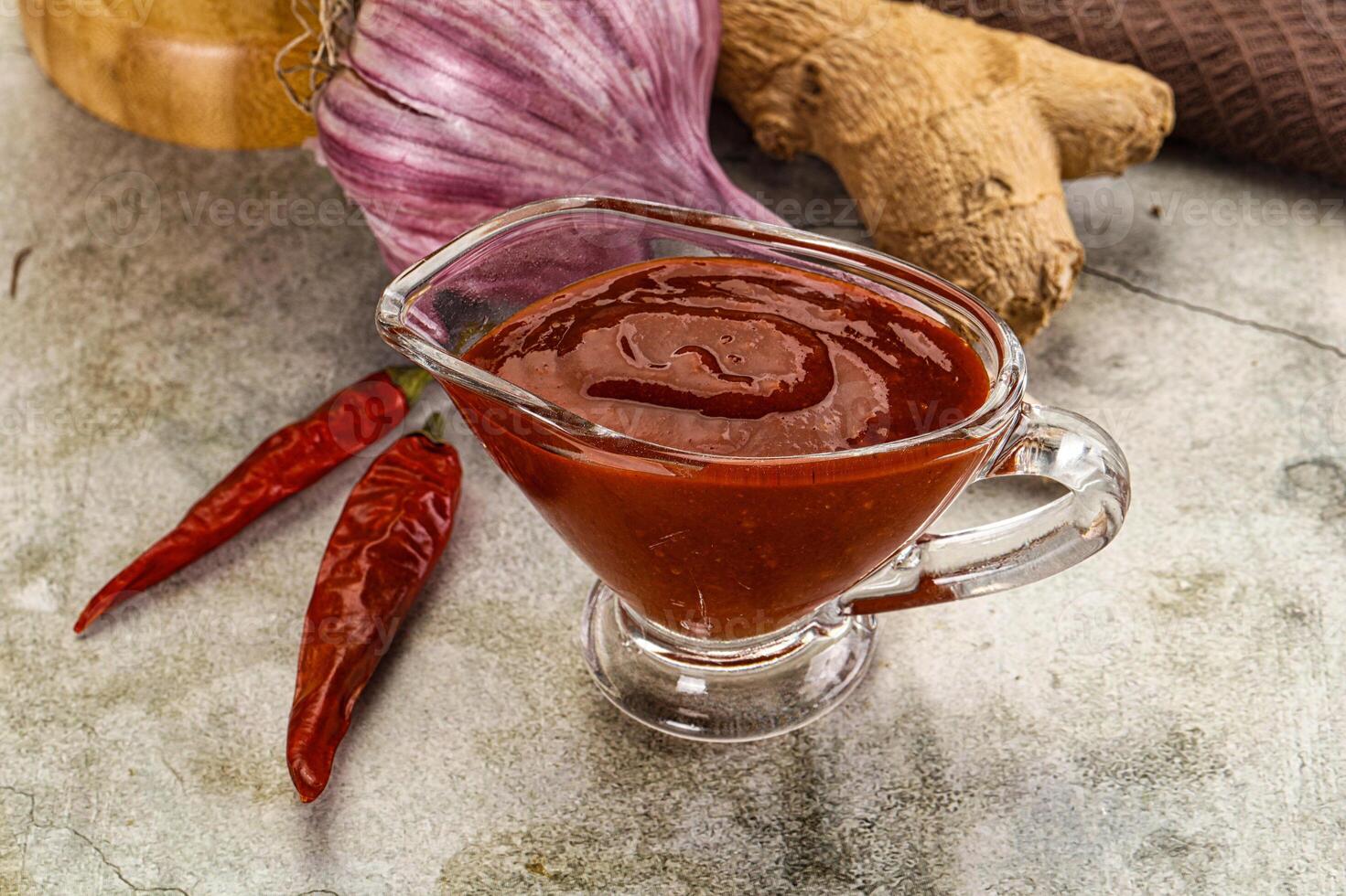 A glass jar with a sauce on it next to some spices photo