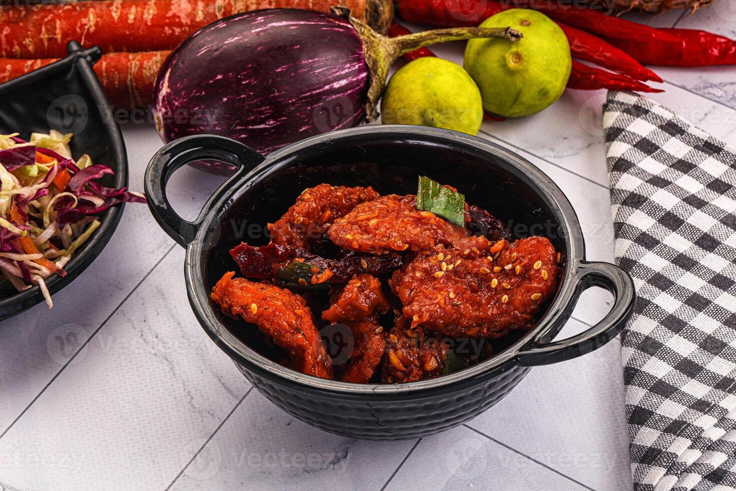 A bowl of food with vegetables and a black bowl with a black lid photo
