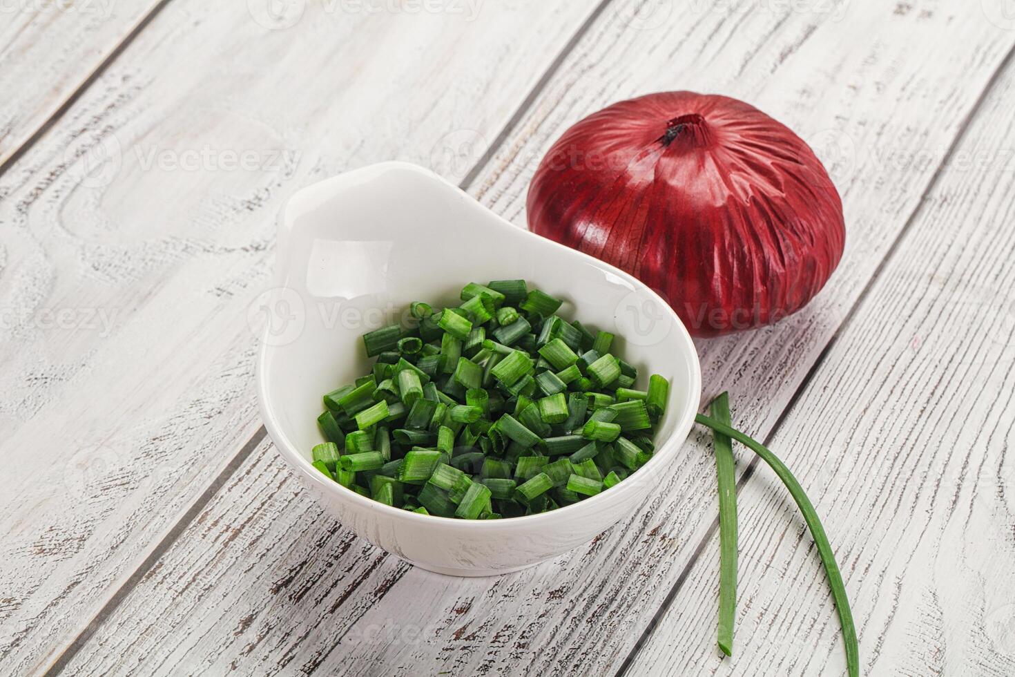 A bowl of chopped green onions and an onion photo