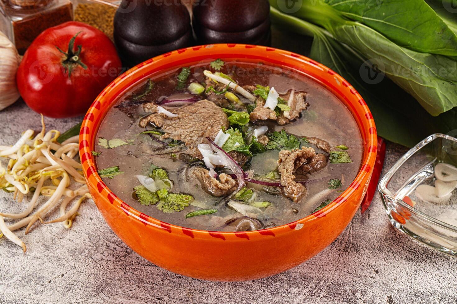 A bowl of soup with meat and vegetables on a table photo