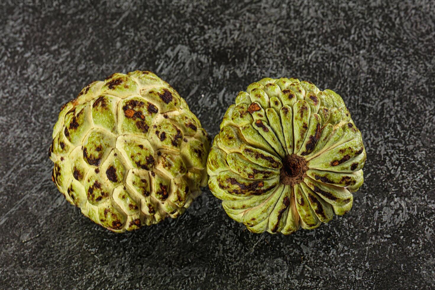 Two green and brown fruit on a black surface photo