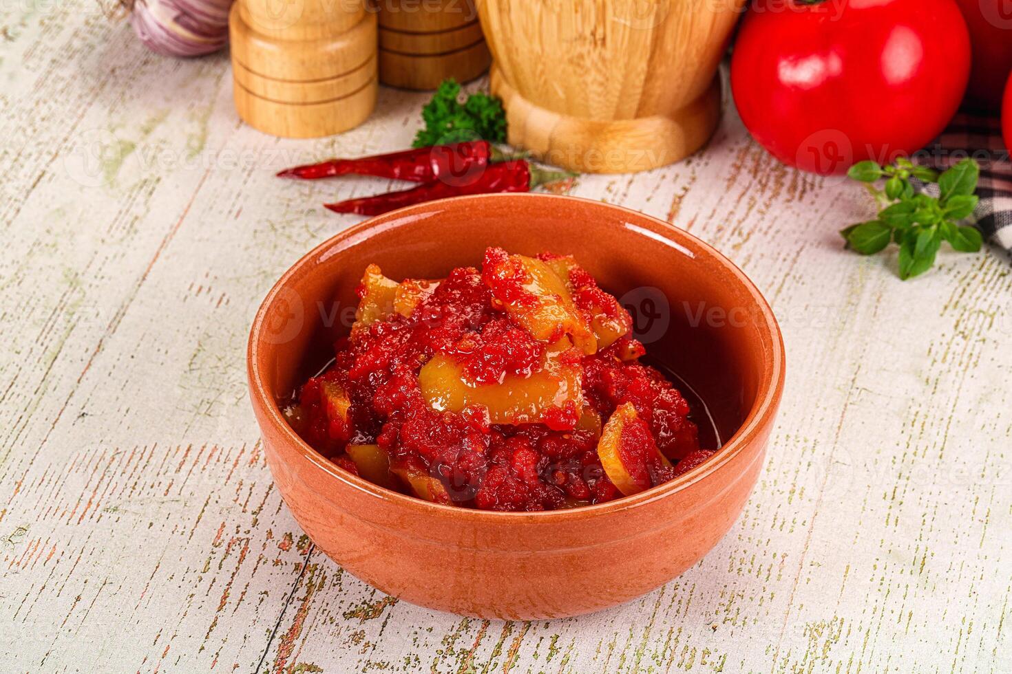 A bowl of tomato sauce with a knife and a tomato photo