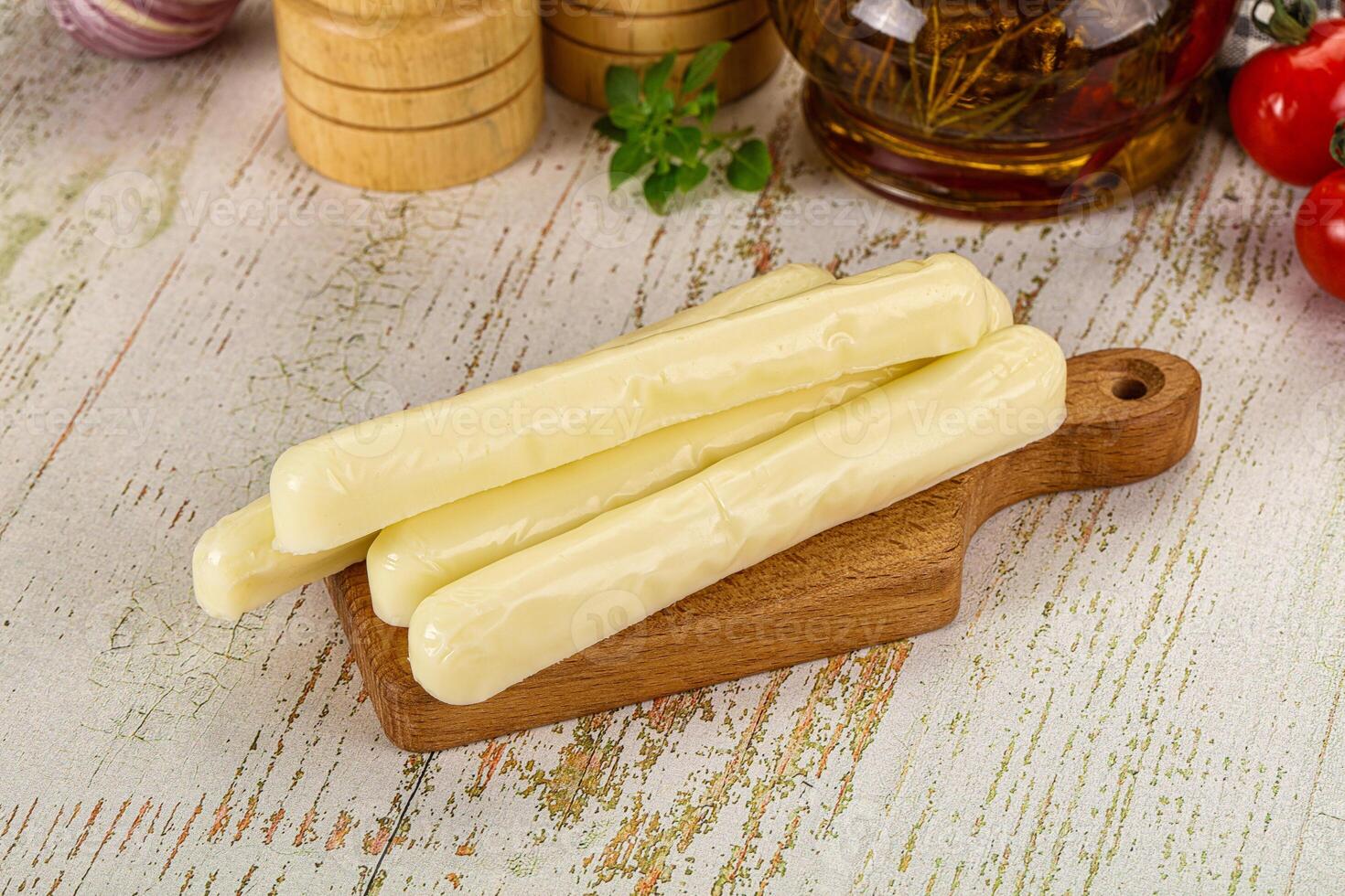 A wooden cutting board with cheese sticks on it photo