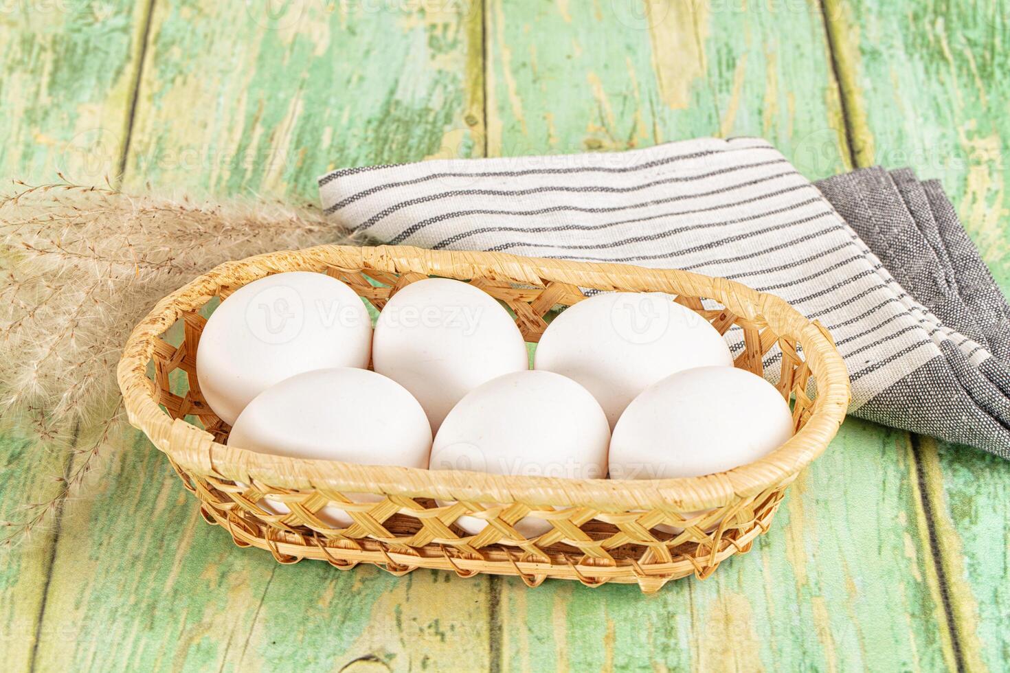 White eggs in a basket on a wooden table photo