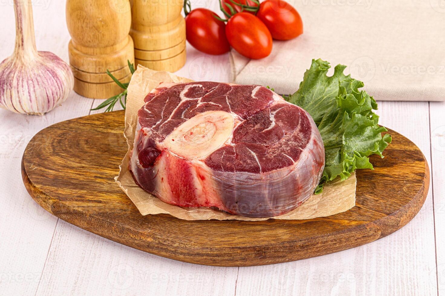A piece of meat on a cutting board with vegetables photo