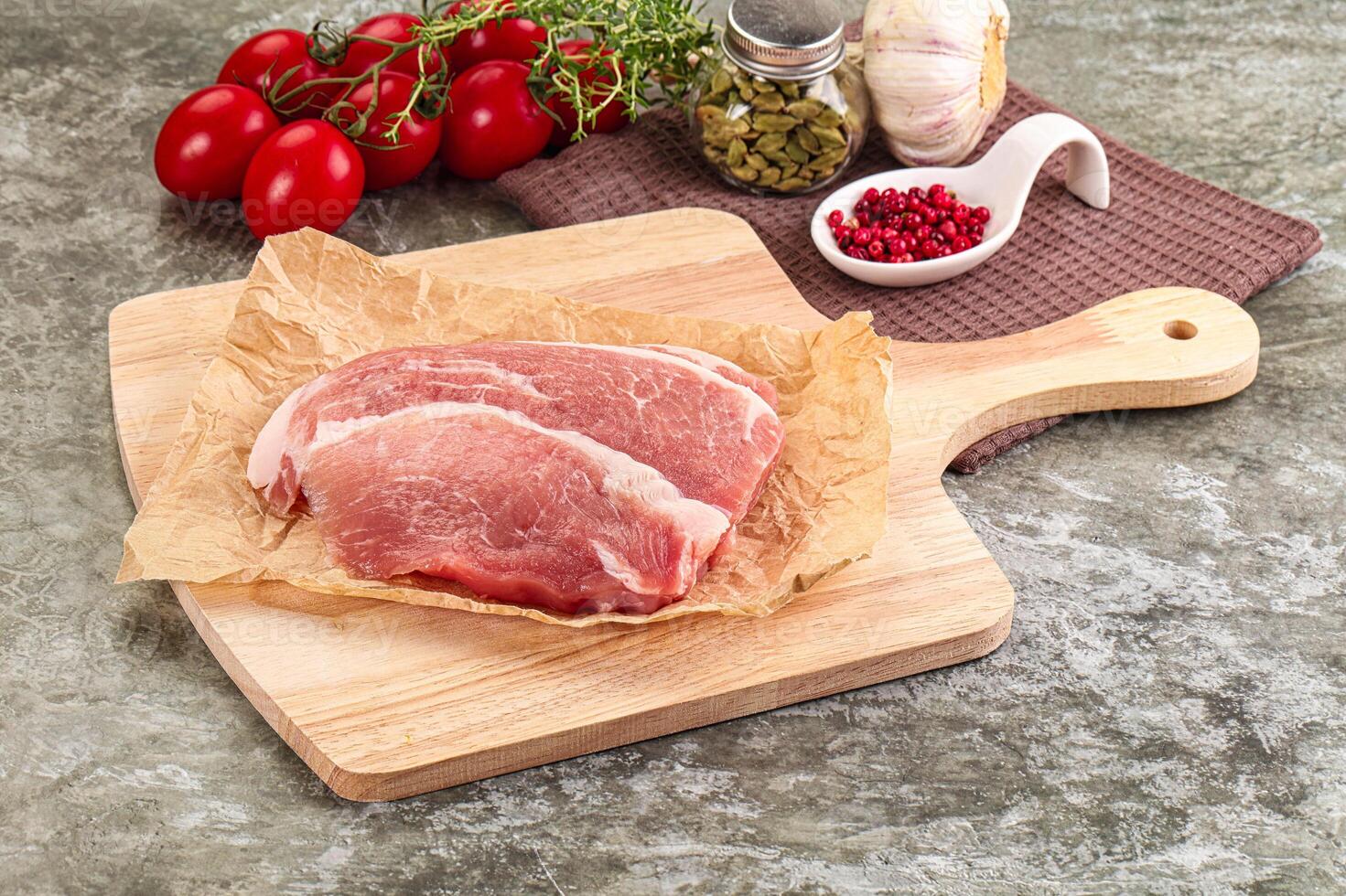 Raw meat on a cutting board with spices and tomatoes photo