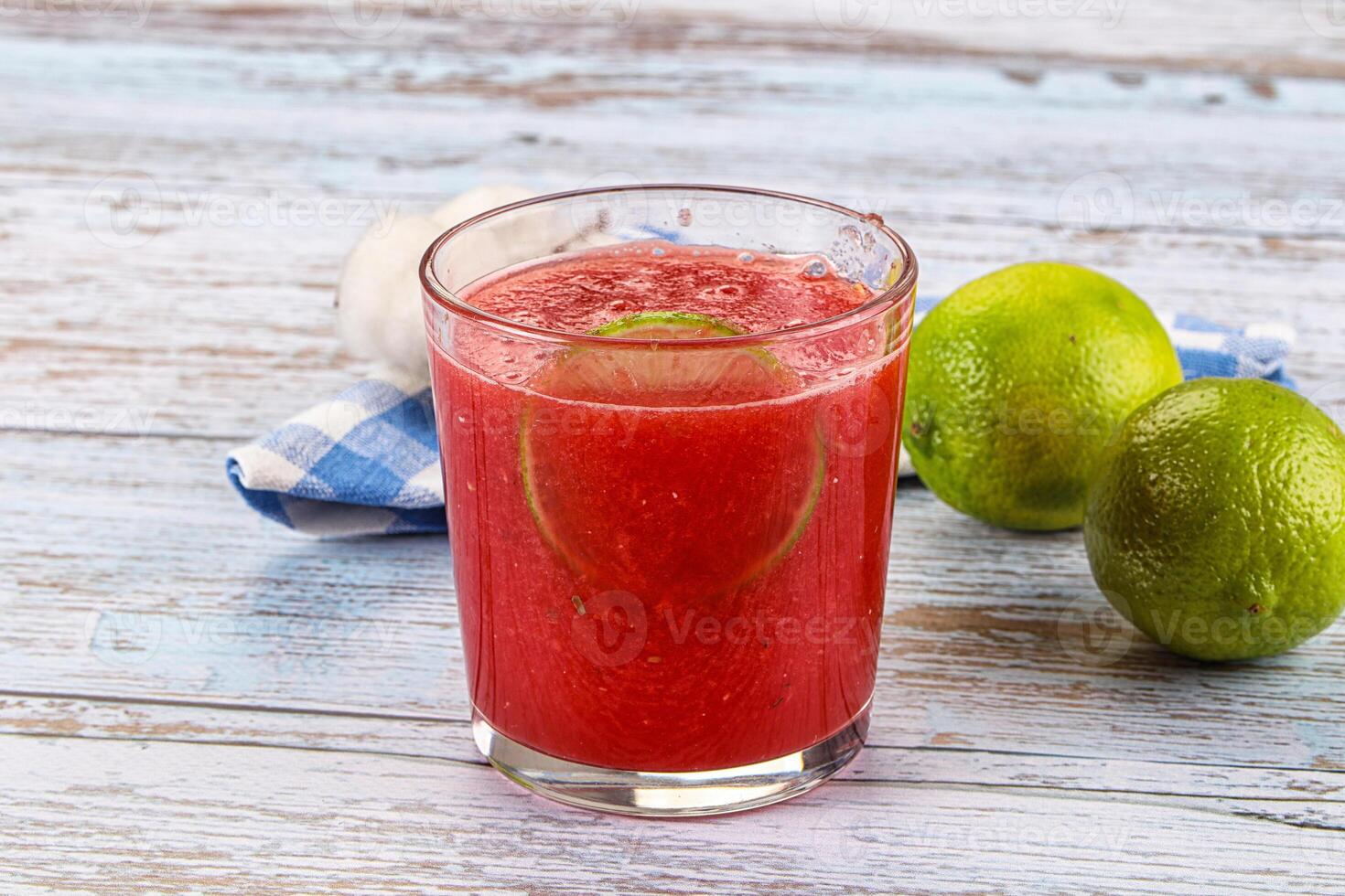 A glass of red juice with lime and a lime photo