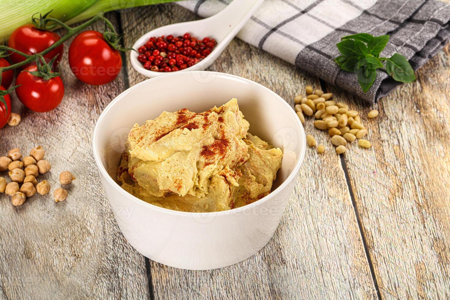 A bowl of hummus with a spoon and a knife photo