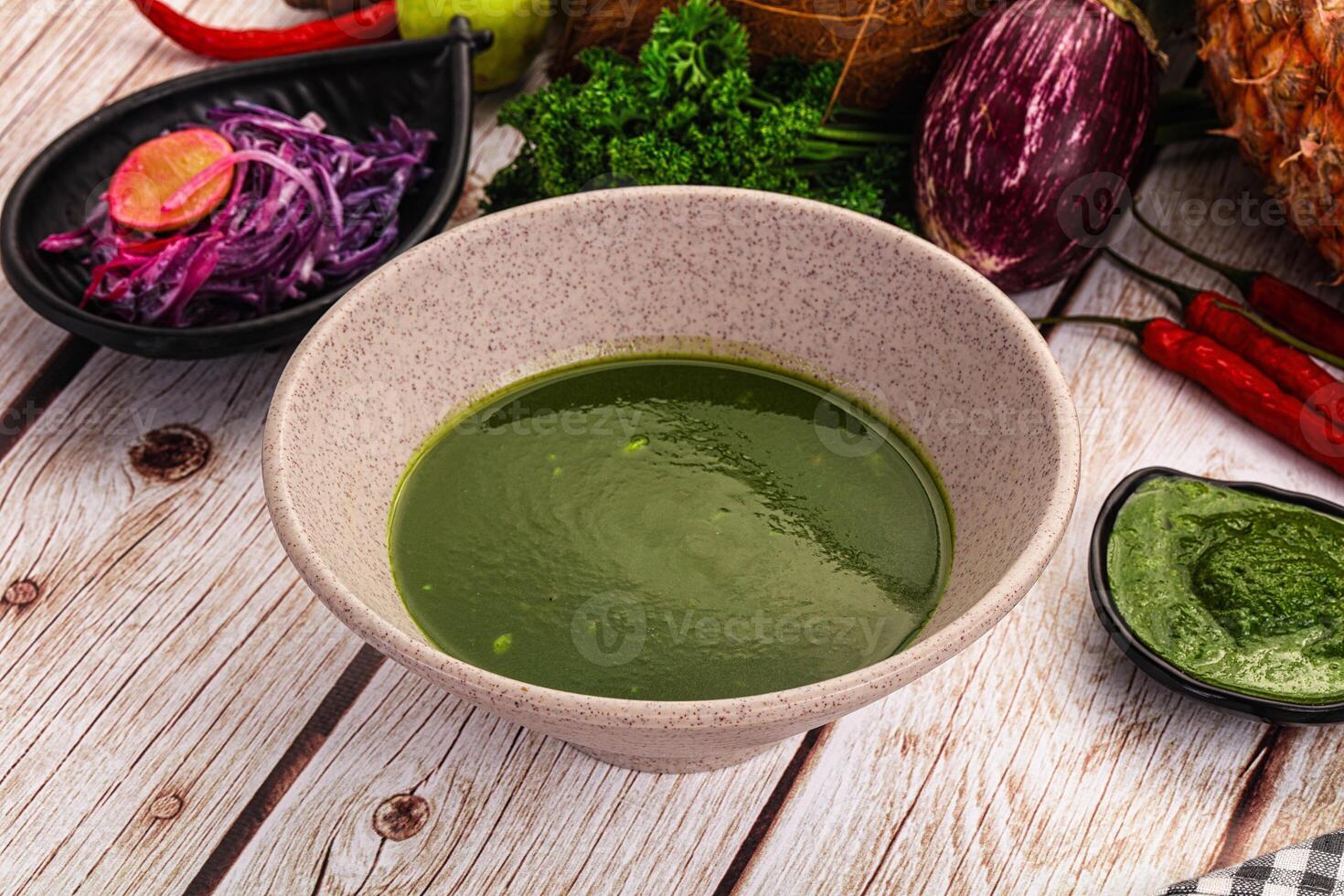 A bowl of green sauce with a pineapple on top photo