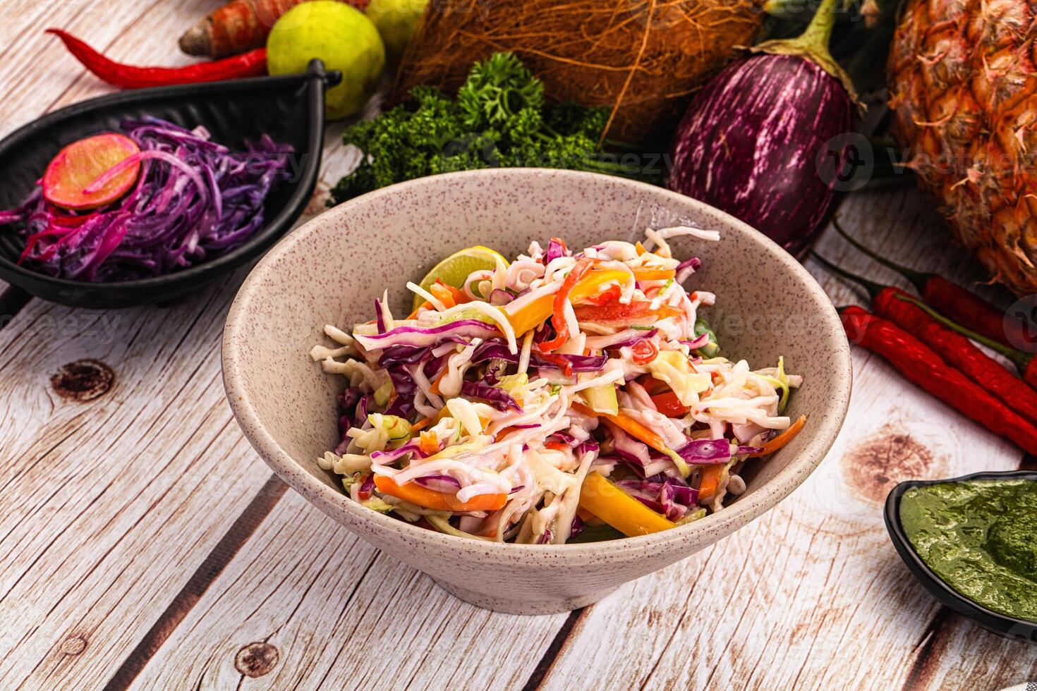 A bowl of salad with vegetables and pineapple on a wooden table photo