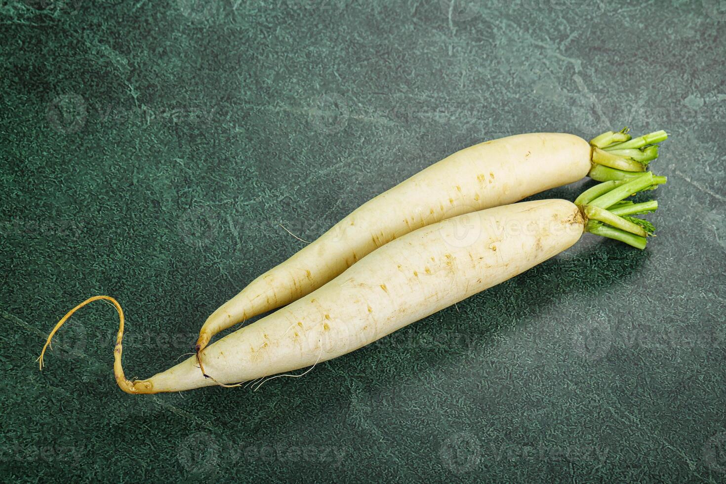 Two white radishes on a green surface photo