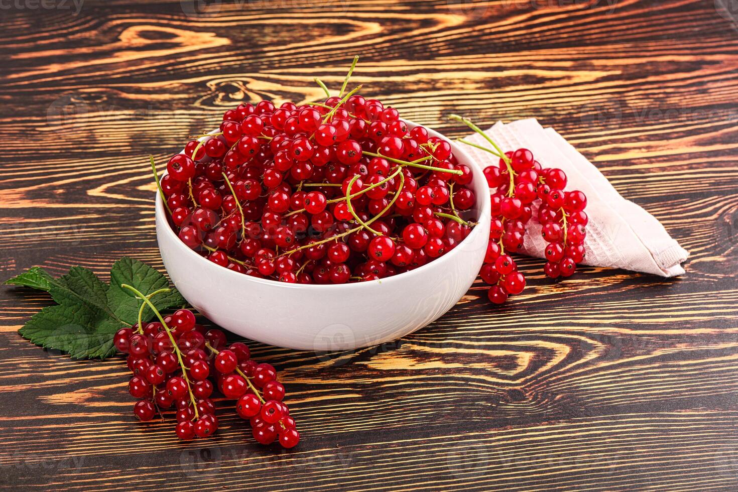 A bowl of red currants on a wooden table photo