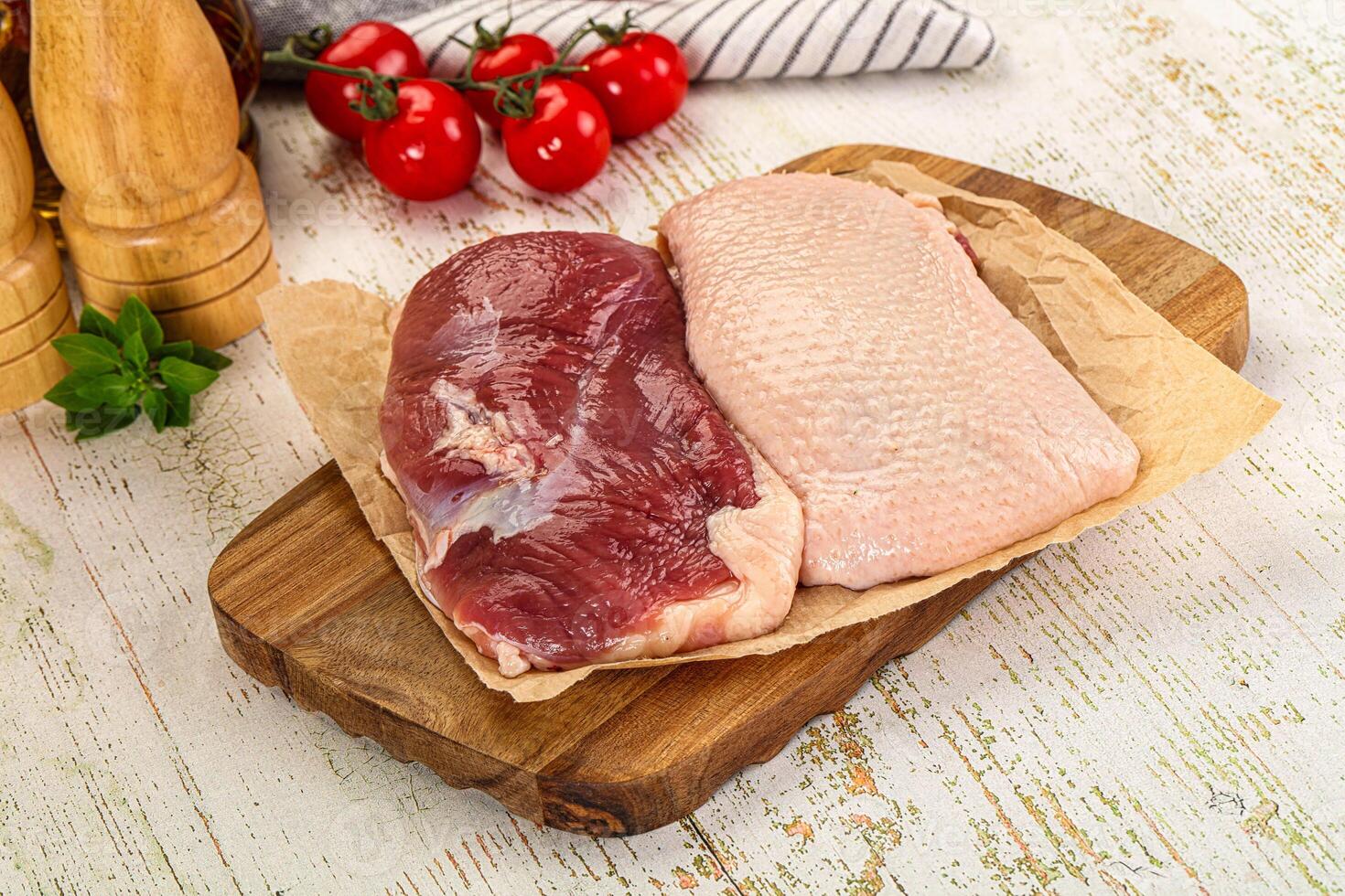 A cutting board with two raw chicken breasts on it photo