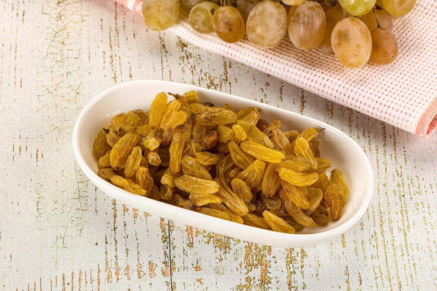 A bowl of raisins and a bowl of grapes photo