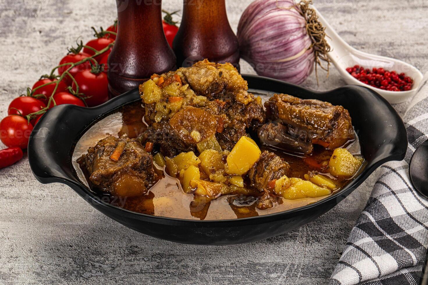 A bowl of stew with meat and potatoes on a table photo