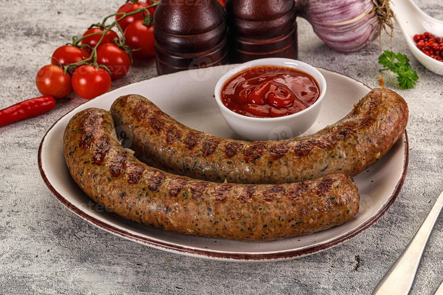 Two sausages on a plate with ketchup and tomatoes photo