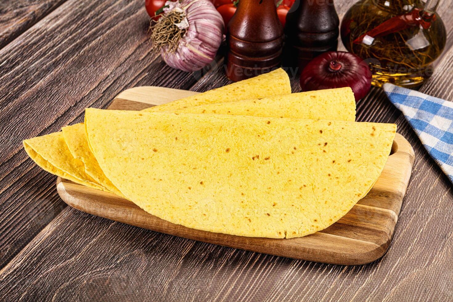 Three tortillas on a wooden cutting board photo