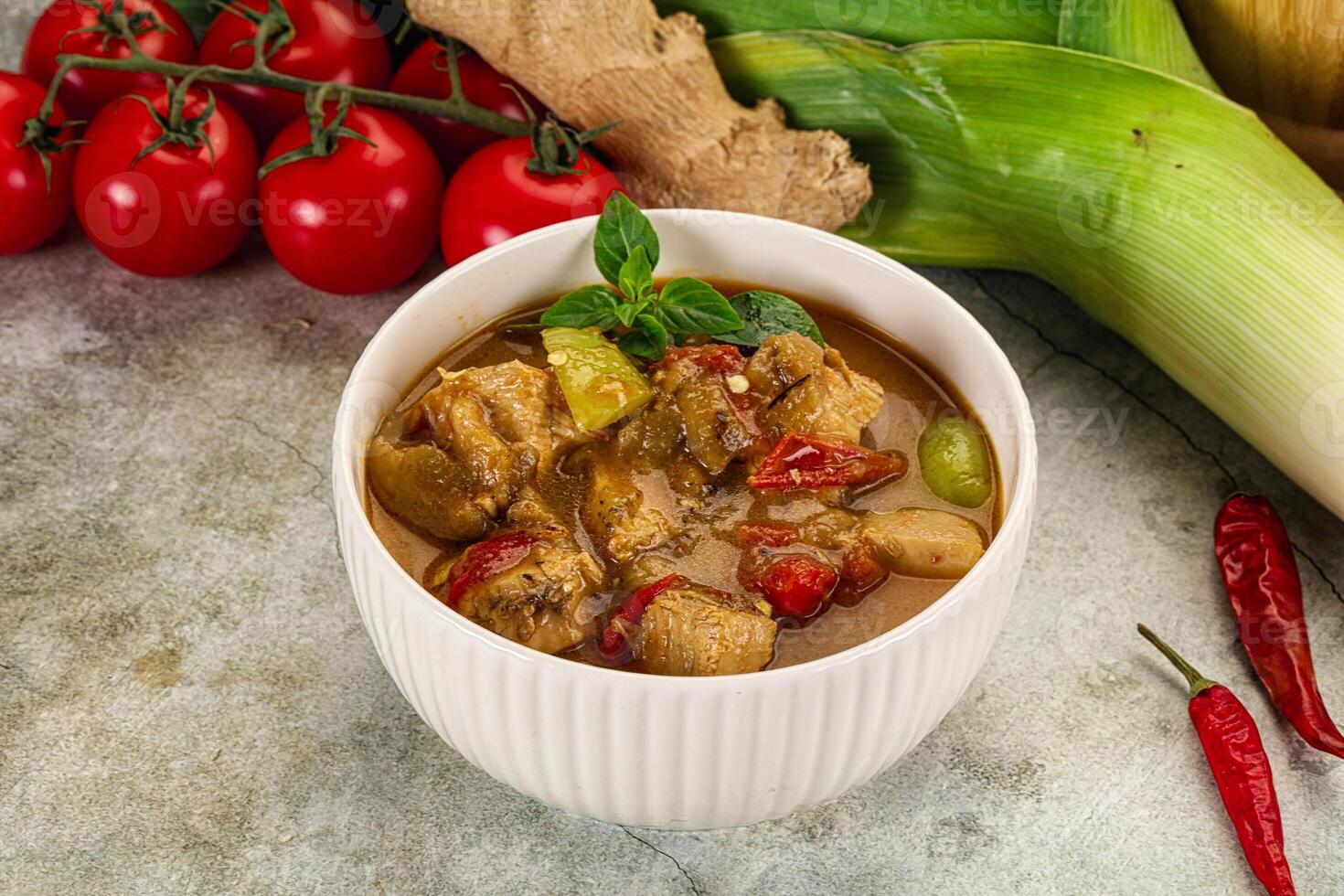 A bowl of curry with vegetables and tomatoes photo