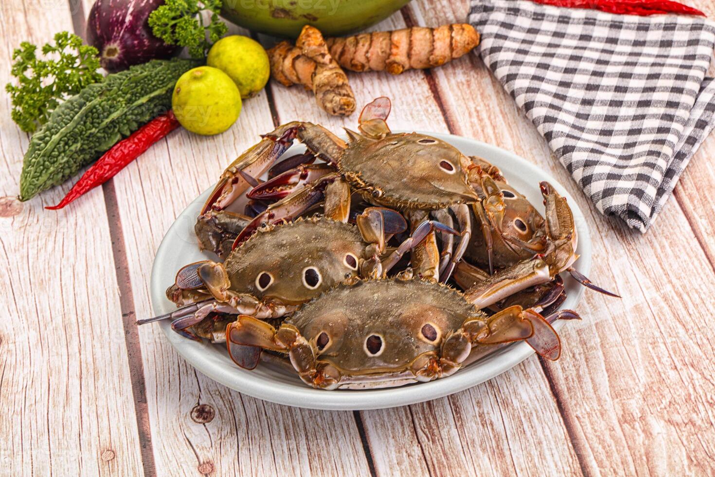 A plate of crabs on a table with other vegetables photo