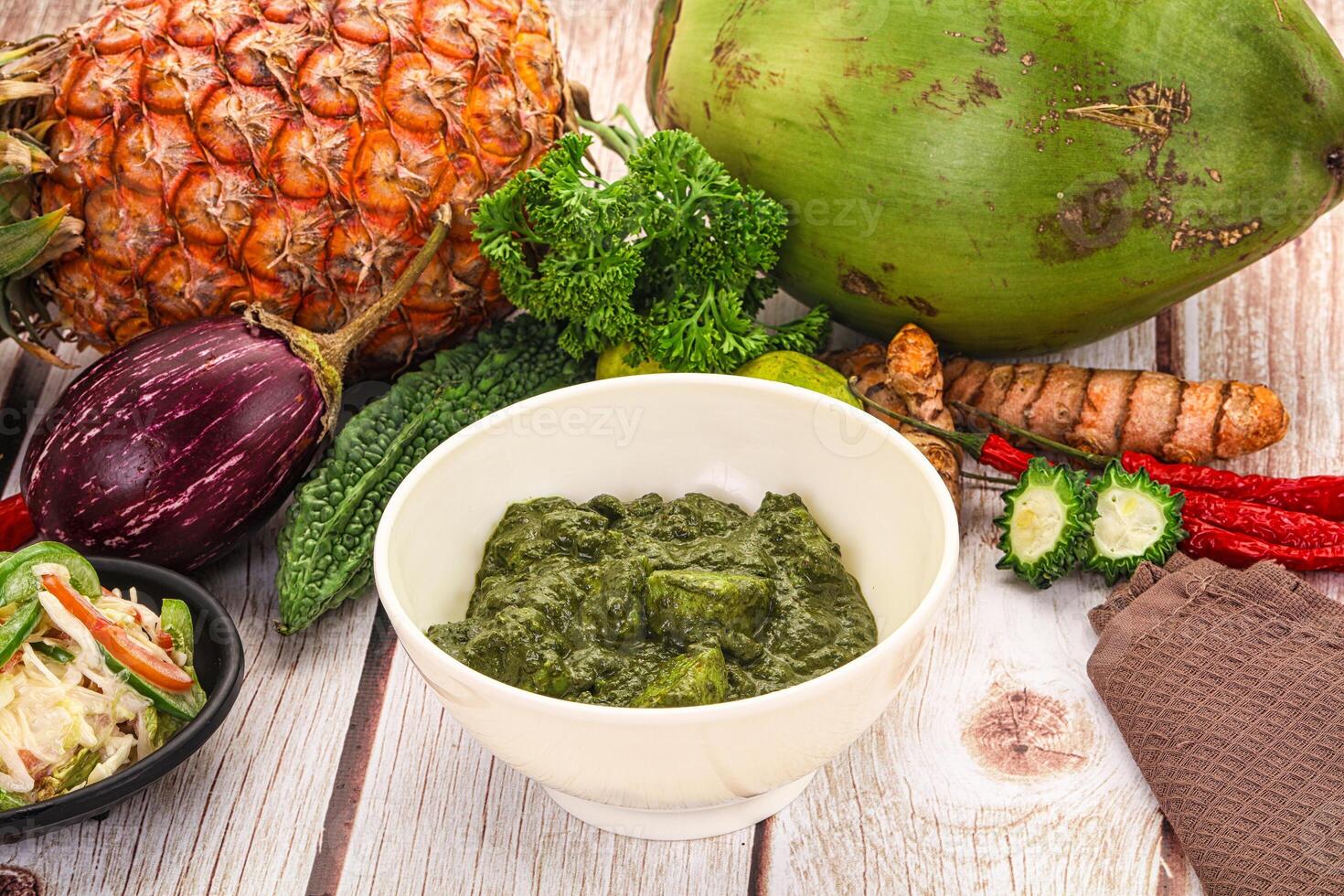 A bowl of green food sits next to a pineapple photo