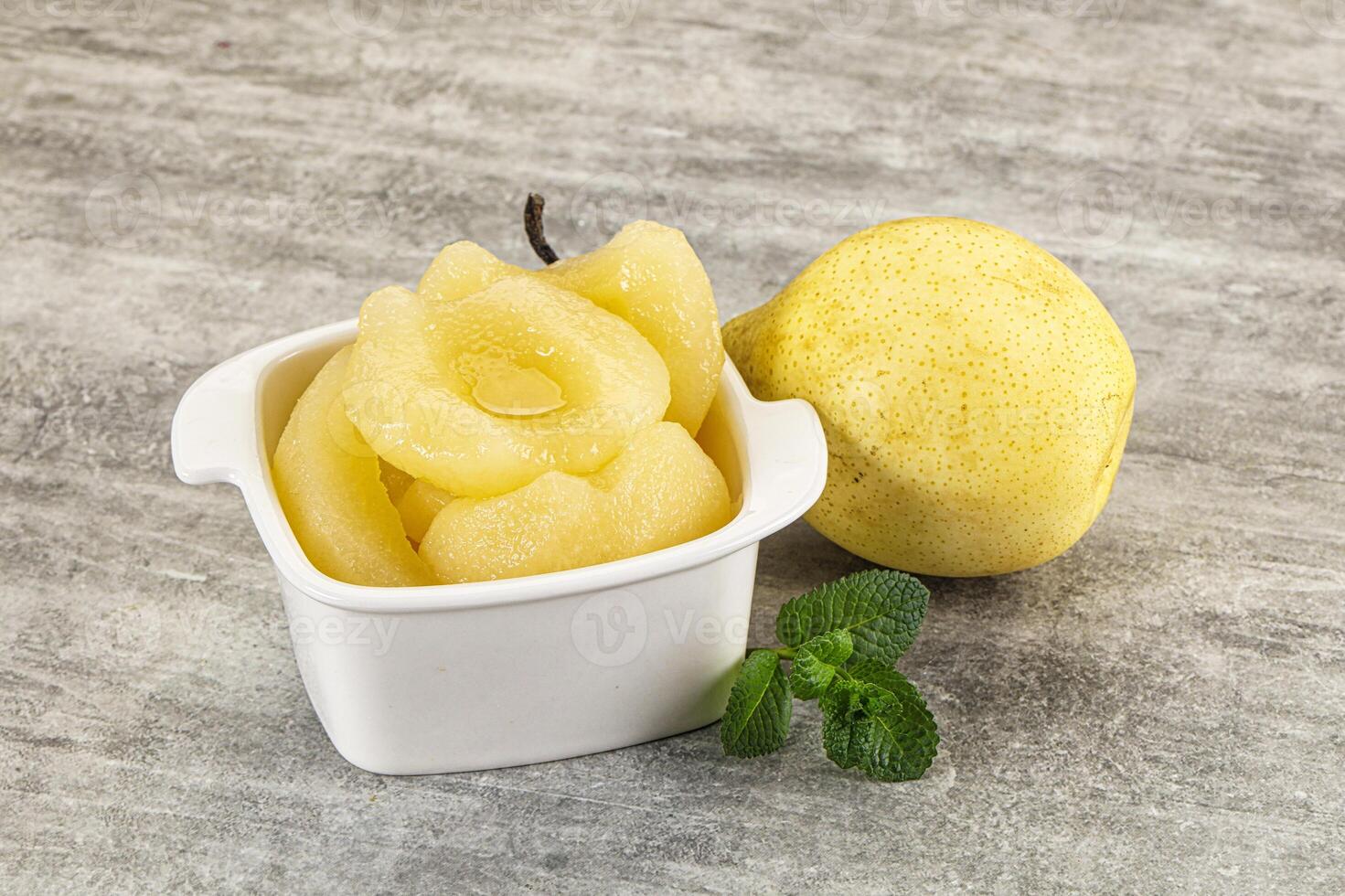 A white cup with a slice of lemon and a small bowl with a slice of pear photo