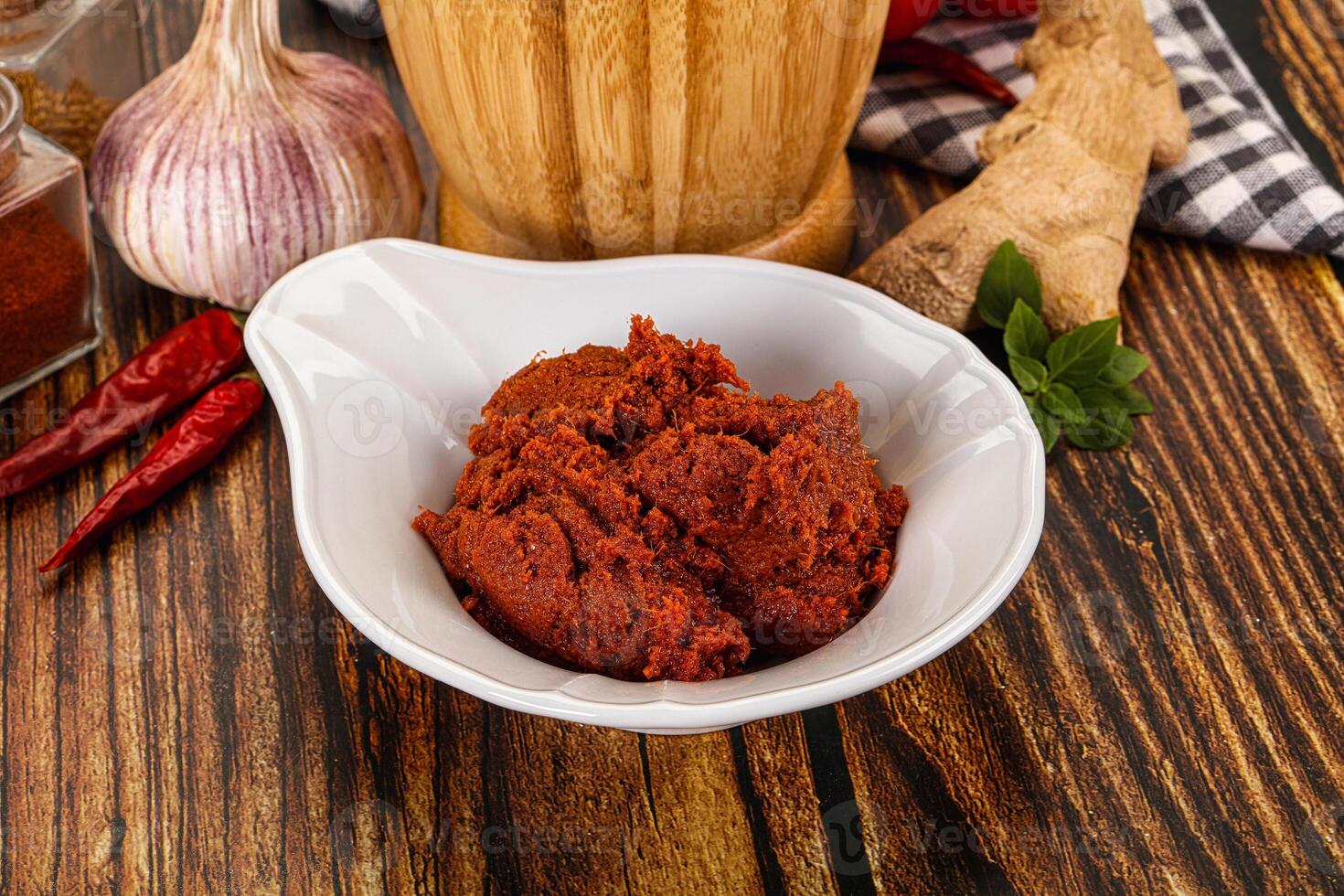 A bowl of red sauce next to a bottle of garlic photo